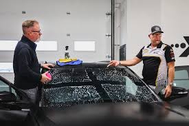 Technician carefully applying Xpel windshield protection film on a vehicle
